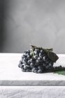 Ramo de uvas con hojas en la mesa - foto de stock