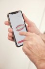 Manos de un hombre irreconocible que demuestra un teléfono inteligente moderno con escaneo de dientes en la oficina del dentista - foto de stock