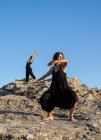 Junge geheimnisvolle Ballerinen in Schwarz tanzen an sonnigen Tagen auf Felsen — Stockfoto