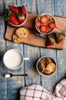 Glas und Flasche Milch und Stapel frischer Kekse auf Holzbrett neben Serviette — Stockfoto