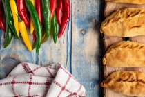 Набір саморобних пиріжків і свіжих зелених і червоних Чилі перець на сірому дерев'яному столі — стокове фото