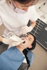 Hands of dentist in gloves using modern equipment for making scan of teeth of female patient in dentist office — Stock Photo