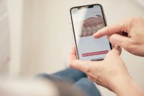 Manos de dentista anónimo demostrando smartphone con escaneo dental a paciente irreconocible en clínica - foto de stock