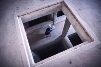 Von oben ein junger Mann in lässigem Outfit, der sich auf dem Betonboden eines schmuddeligen Gebäudes windet — Stockfoto