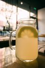Canecas de vidro com deliciosa bebida fresca de limão no fundo desfocado — Fotografia de Stock