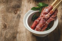 Gressinis with spanish typical serrano ham in pot on rustic wooden table — Stock Photo