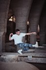 Junger Kerl in stylischem Outfit tanzt modernen Tanz im alten schäbigen Gebäude — Stockfoto