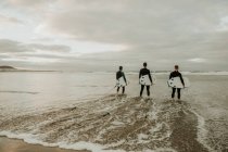 Люди с доской для серфинга, гуляющие у моря — стоковое фото