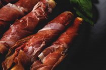 Close-up of gressinis with spanish typical serrano ham on dark background — Stock Photo