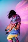 Vista lateral da jovem mulher na roupa da moda dançando sob iluminação colorida — Fotografia de Stock