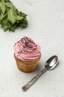 Delicioso cupcake rosa caseiro no fundo branco com colher de chá — Fotografia de Stock