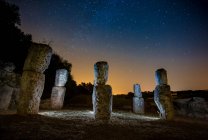 Monumenti rupestri evidenziati da luci e cielo mozzafiato con stelle di notte — Foto stock