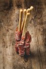 Gressinis with spanish typical serrano ham on rustic wooden table — Stock Photo