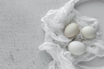 Ovos brancos em tecido na mesa de madeira — Fotografia de Stock