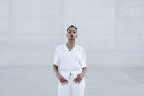 Mode kurzhaarige ethnische Modell in weißem Outfit posiert gegen graue Wand — Stockfoto