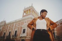 Confiante afro-americano elegante mulher em jaqueta posando na rua — Fotografia de Stock