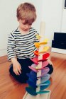 Blonder süßer Junge spielt mit Waldorf klingendem Turm mit Murmeln — Stockfoto