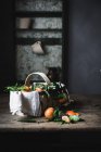 Ripe mandarins with leaves and basket on rough wooden table — Stock Photo