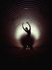 Silhouette de ballet féminin mince dansant à l'intérieur d'une pipe grunge sombre — Photo de stock