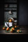 Mandarinas maduras con hojas y cesta sobre mesa de madera rugosa - foto de stock