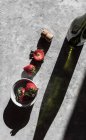 Frische Erdbeeren in Schüssel und auf grauer Oberfläche mit einer Flasche Wein — Stockfoto