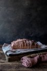 Fresh tasty orange cake with poppy seeds and topping on craft paper on black background — Stock Photo