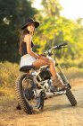 Attractive asian woman sitting on motorbike in countryside — Stock Photo
