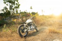 Motorcycle parked on path in countryside in sunlight — Stock Photo