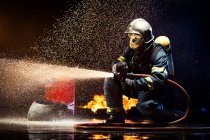 Pompier anonyme combattant le feu avec de l'eau — Photo de stock