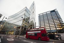 Autobus rosso su strada vicino a edifici moderni illuminati su strada di Londra — Foto stock