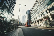 Красный автобус и велосипедная парковка на городской улице в Лондоне — стоковое фото