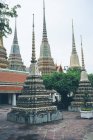 Ornamentale Pyramiden schmücken Hof des erstaunlichen orientalischen Tempels gegen grauen Himmel in Thailand — Stockfoto