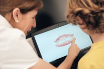 Dentista femminile che dimostra la scansione dei denti sullo schermo del computer portatile al bambino in clinica moderna — Foto stock