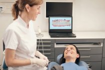Dentista feminino demonstrando varredura de dentes na tela do laptop para o menino na clínica moderna — Fotografia de Stock