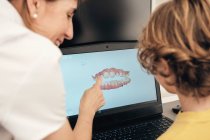 Zahnärztin demonstriert Gebiss-Scan auf Laptop-Bildschirm für kleinen Jungen in moderner Klinik — Stockfoto
