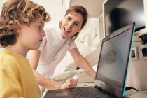 Жінка-стоматолог демонструє сканування зубів на екрані ноутбука для хлопчика в сучасній клініці — стокове фото
