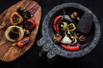 Delicious roasted vegetables in mortar and on wooden board — Stock Photo