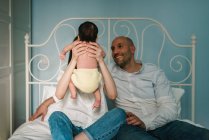 Родители обнимают ребенка в постели — стоковое фото