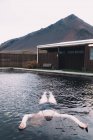 Frau ruht sich im Wasser des Schwimmbeckens in der Natur mit trockenem Berg im Hintergrund aus — Stockfoto