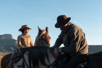 Uomo e donna a cavallo contro il cielo al tramonto nel ranch — Foto stock