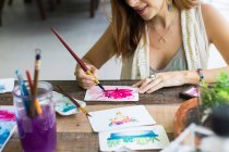 Artista latina pintando con acuarela en su estudio - foto de stock
