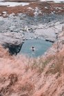 Donna che riposa in acqua vicino a scogliera sulla costa asciutta tra le pietre — Foto stock