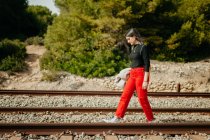 Hübsche junge Frau in stylischem Outfit schaut auf Schienen herab — Stockfoto