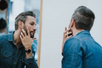 Reflexão no espelho de bonito elegante masculino verificando barba no salão — Fotografia de Stock