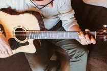 Nahaufnahme eines Mannes, der auf dunklem Hintergrund Gitarre spielt — Stockfoto