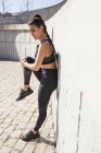Brunetta donna stretching muscoli in giornata di sole con una parete di granito su sfondo — Foto stock