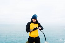 Взрослый мужчина с бородой обвязывает руку бинтом, стоя у моря во время тренировки по кикбоксингу на открытом воздухе — стоковое фото