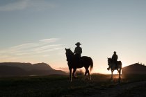 Чоловік і жінка катаються на конях проти заходу сонця небо на ранчо — стокове фото