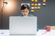 Geschäftsfrau arbeitet am Laptop, während sie im modernen Büro am Schreibtisch sitzt — Stockfoto