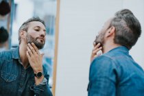 Віддзеркалення в дзеркалі красивої стильної чоловічої перевірки бороди в салоні — стокове фото